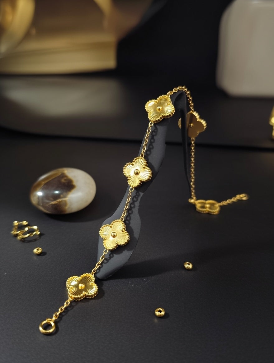 A dainty gold chain bracelet featuring three textured four-leaf clover charms