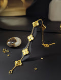 A dainty gold chain bracelet featuring three textured four-leaf clover charms