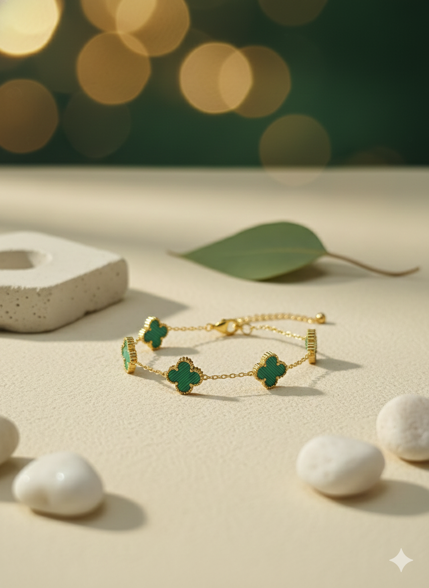 A gold chain bracelet with three green malachite four-leaf clover charms