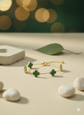 A gold chain bracelet with three green malachite four-leaf clover charms