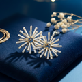 A pair of floral-inspired white enamel earrings featuring radiating petals and a hollow center.