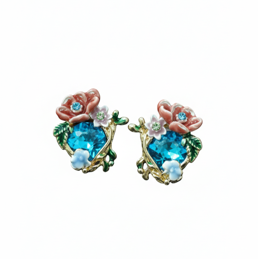 A pair of gold-toned stud earrings featuring large teal faceted crystals surrounded by pink, white, and peach enamel flowers and green leaves