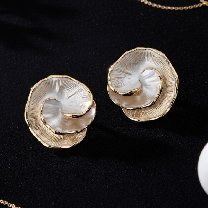 A pair of large, multi-layered gold floral stud earrings with iridescent pearlescent centers
