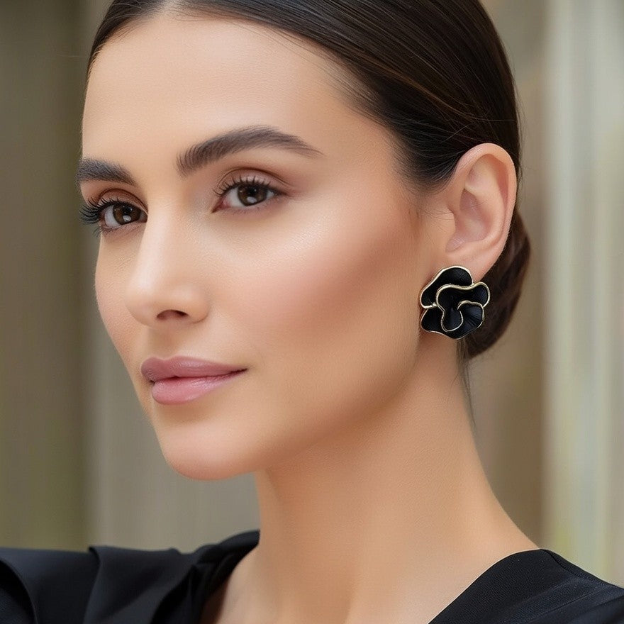 Close-up of black flower earrings next to white pearls.