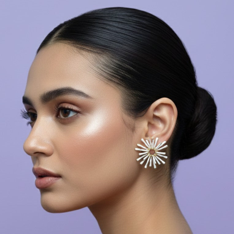 Close-up of textured white spiky earrings with gold accents