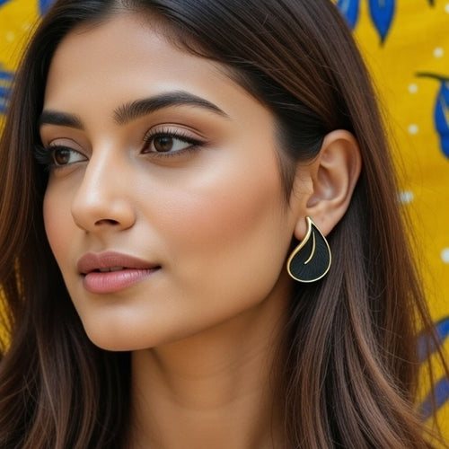 Elegant black and gold teardrop earrings on a lavender background
