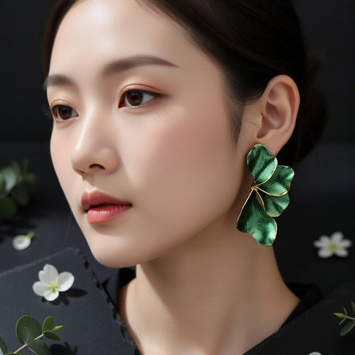 Elegant pair of sculptural botanical earrings on a dark textured surface