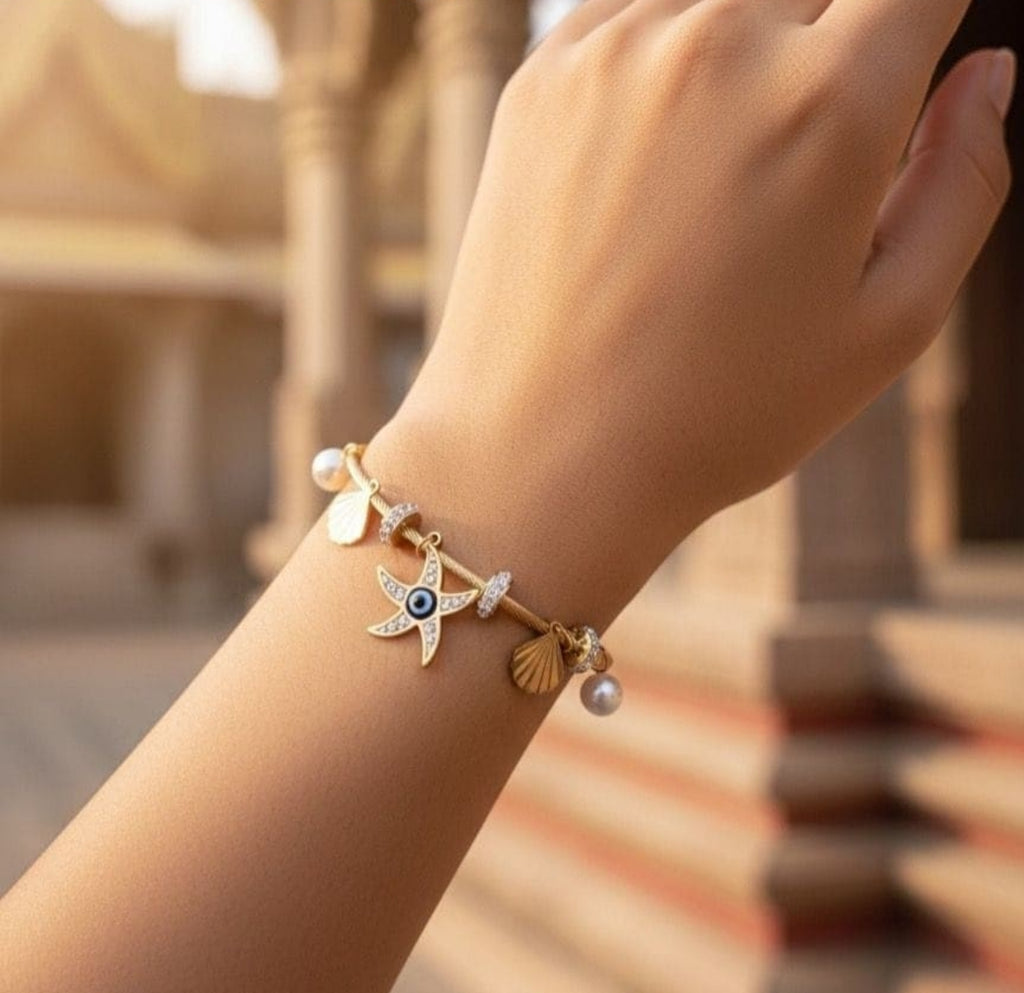 Nautical-themed gold bangle with dangling shell and pearl charms