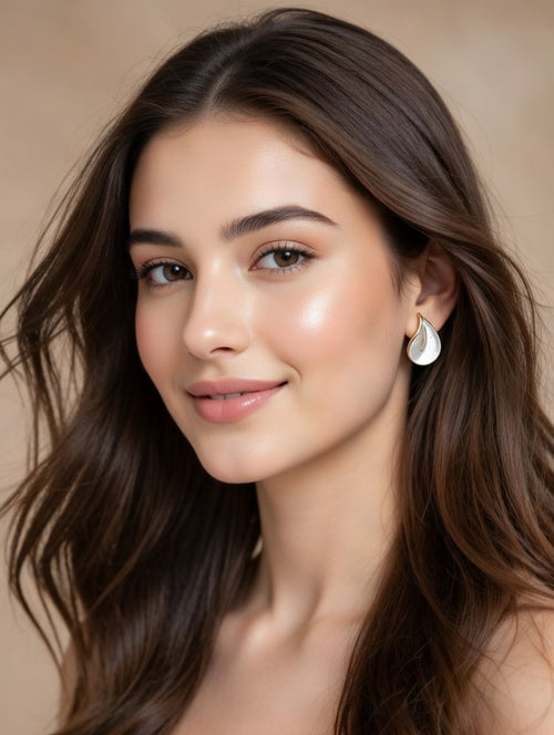 Pair of ivory teardrop leaf studs next to white jasmine flowers
