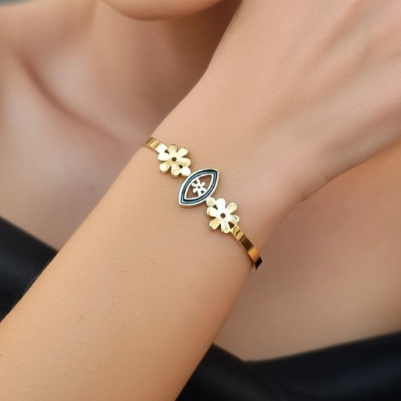 Polished gold bracelet with an open-eye design and floral accents